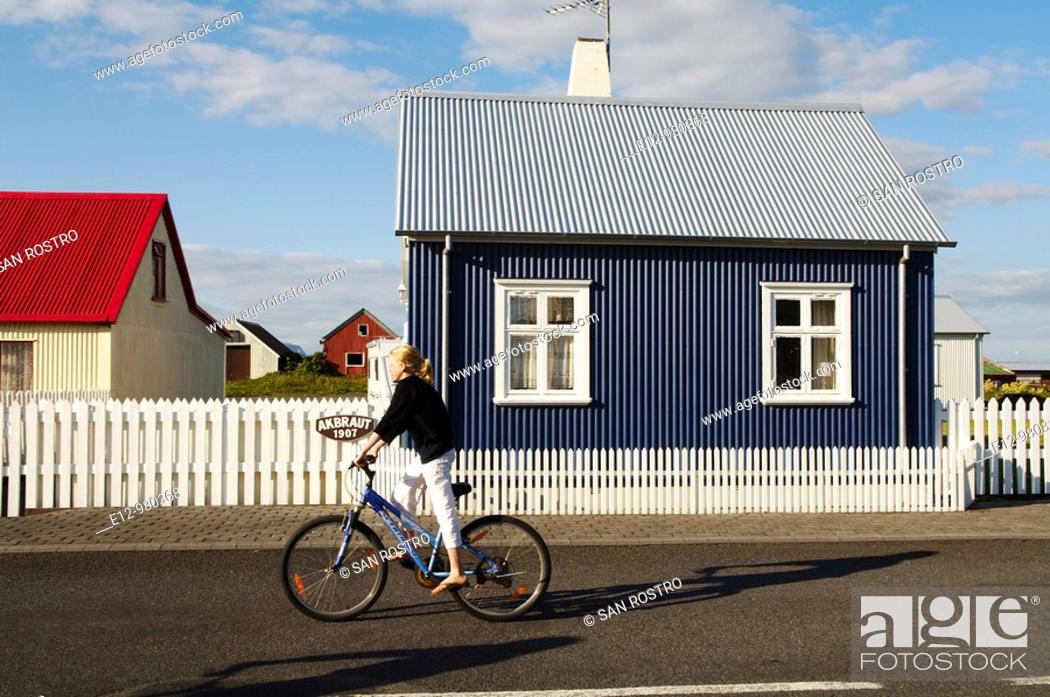Stock Photo: Iceland, Eyrarbakki village old houses, kids playing in the street with bicycle.