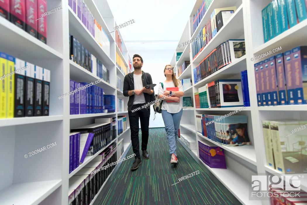 Stock Photo: happy students group in school library selecting books to read and walking.