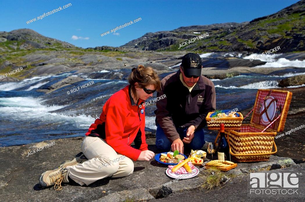 Stock Photo: A couple enjoying a picnic beside a waterfall with a Helicopter in the background in the Mealy Mountains, Southern Labrador, Newfoundland & Labrador, Canada.