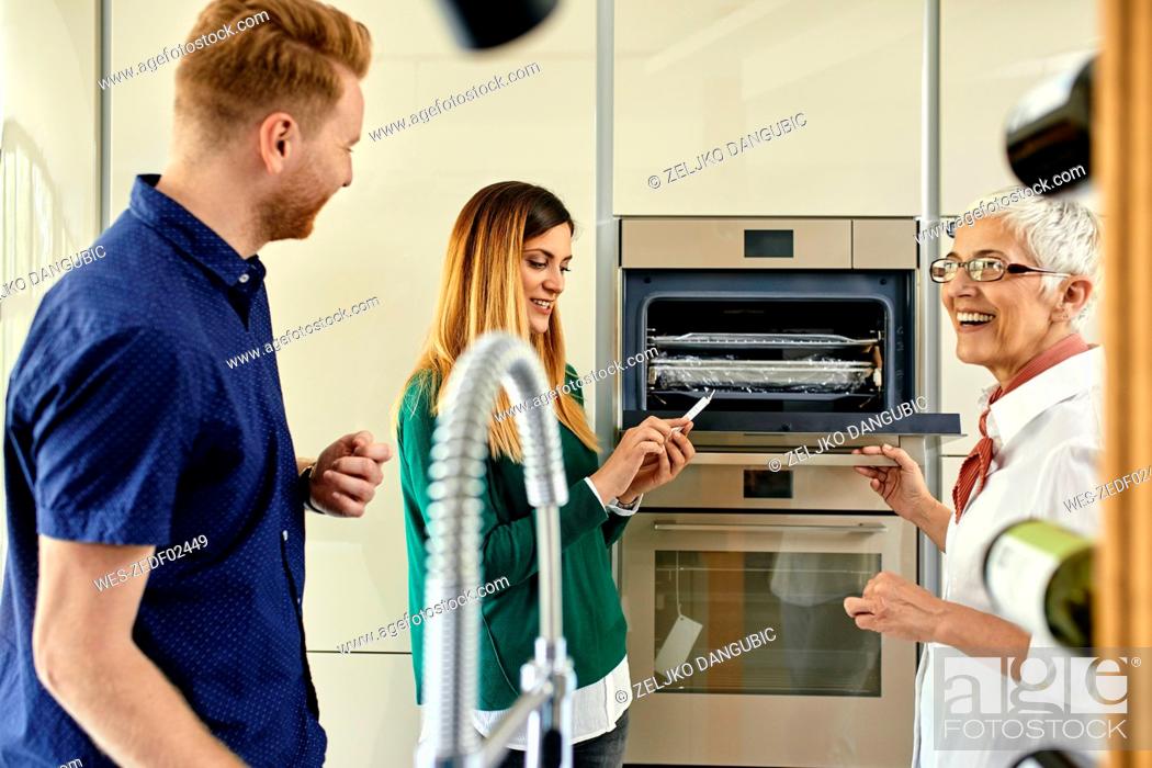 Stock Photo: Shop assistant explaining oven to couple shopping for a new kitchen in showroom.