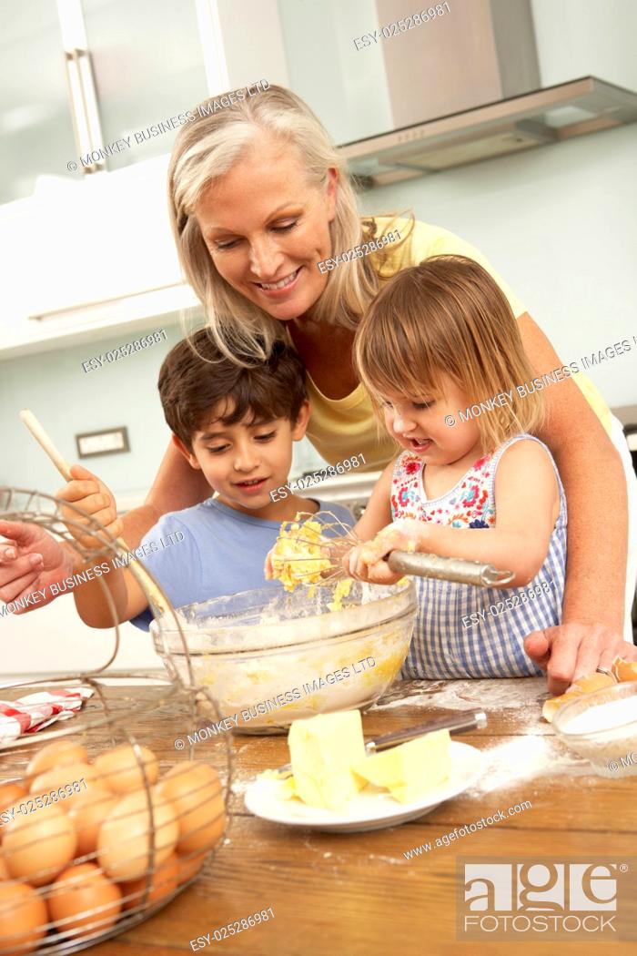 Stock Photo: Grandchildren Helping Grandmother To Bake Cakes In Kitchen.