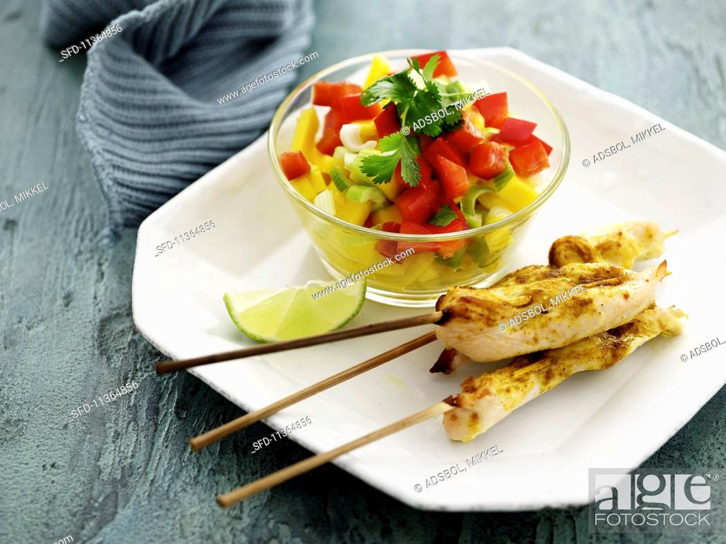Stock Photo: Chicken skewers with curry served with a mango and pepper salad with coriander.