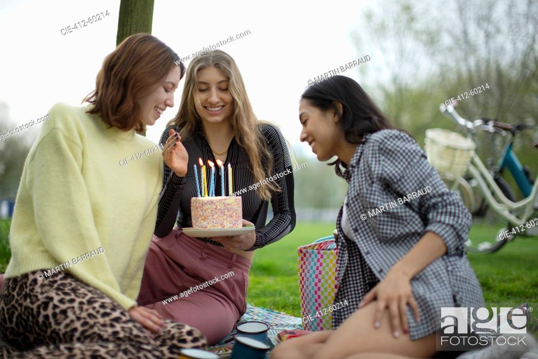 Stock Photo: Happy young women friends celebrating birthday with cake in park.