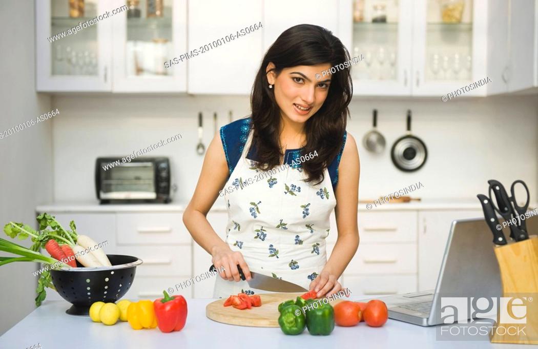 Imagen: Woman chopping tomatoes in the kitchen.