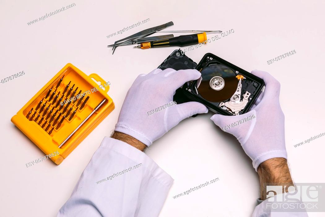 Stock Photo: Hands of a technician with gloves repairing a hard drive. Technology maintenance concept.