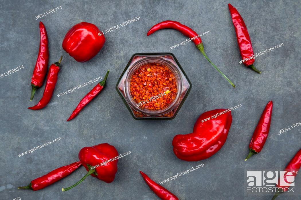 Stock Photo: Various red chili pods and glass of chili flakes.