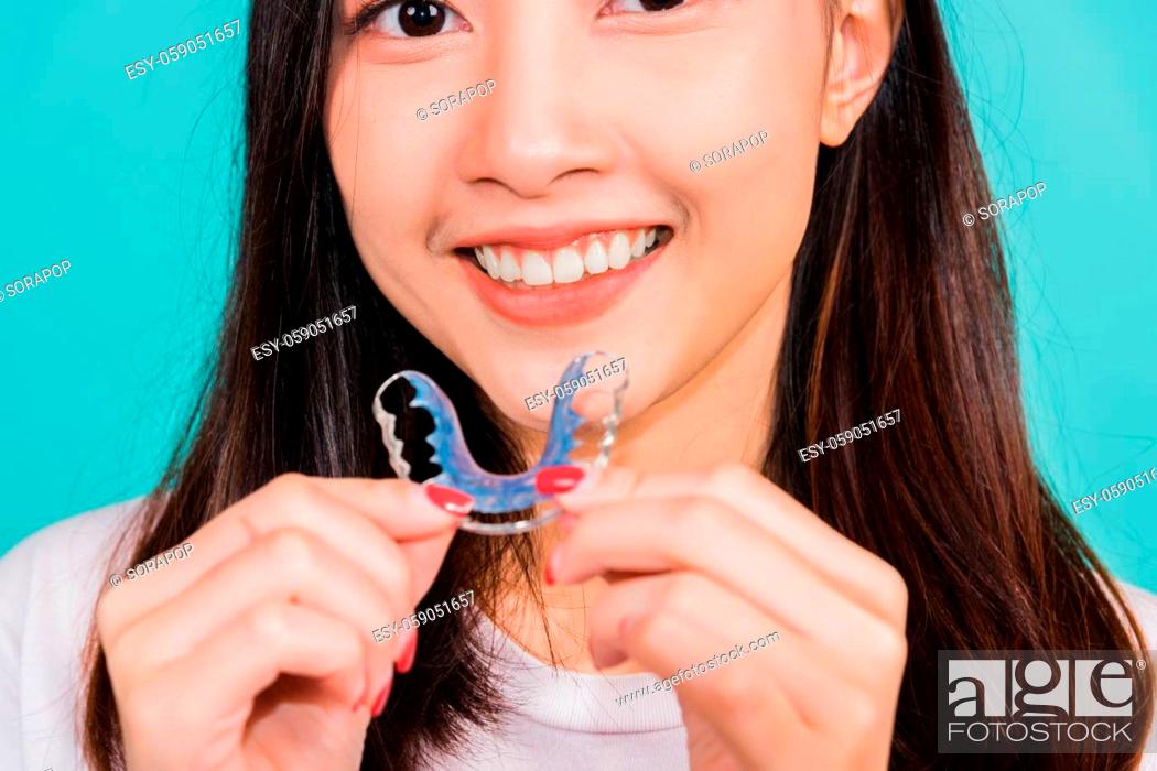 Stock Photo: Teeth retaining tools after removable braces, Portrait young Asian beautiful woman smiling holding silicone orthodontic retainers for teeth.