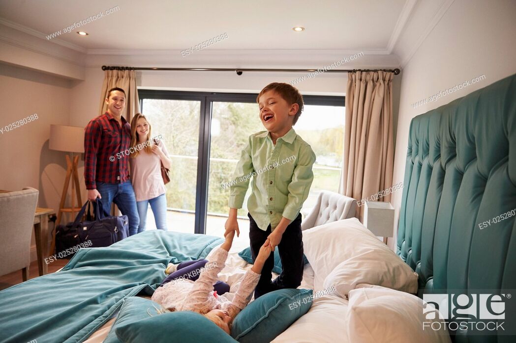 Stock Photo: Family On Vacation With Children Playing On Hotel Bed.
