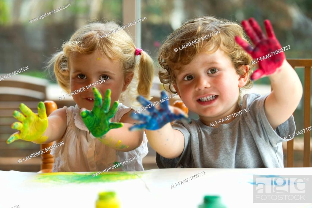 Stock Photo: Little girl and boy showing hands covered in paint, portrait.