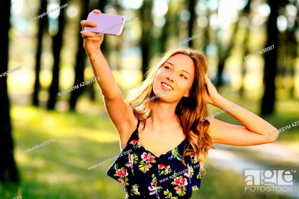 Photo de stock: Happy girl makes selfie on a smartphone.