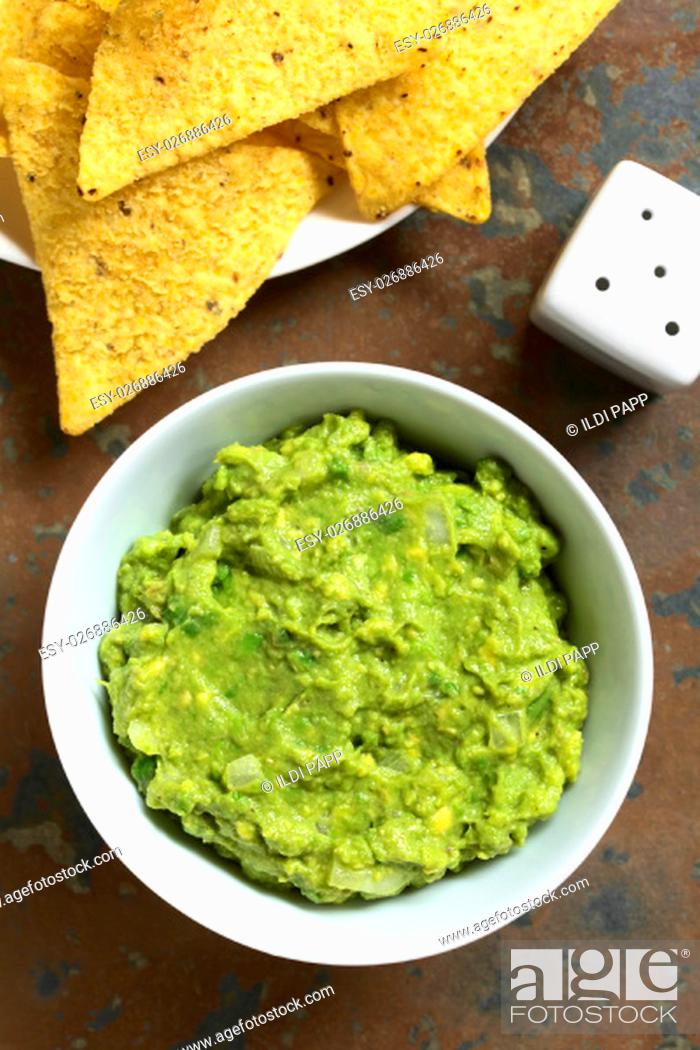 Stock Photo: Avocado dip or guacamole in bowl with corn tortilla chips, photographed overhead with natural light (Selective Focus, Focus on the avocado dip and the tortilla.