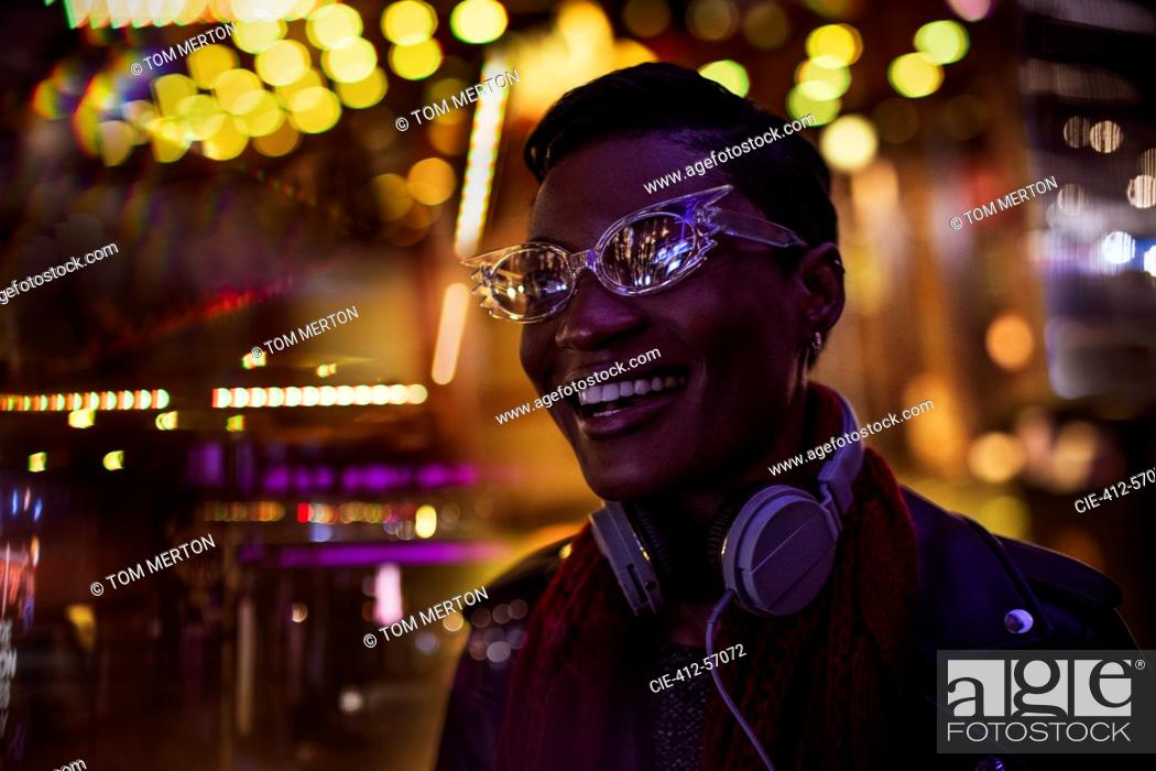 Stock Photo: City lights around happy young woman in funky eyeglasses.