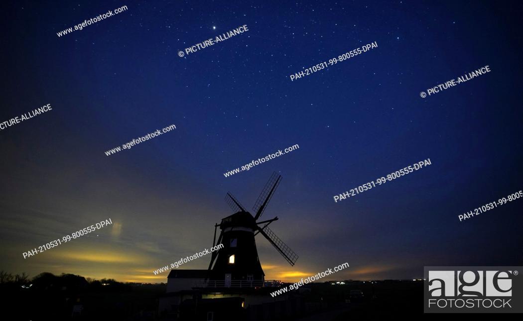 Stock Photo: 10 May 2021, Schleswig-Holstein, Pellworm: The starry sky can be seen above the Nordermühle on the island of Pellworm. A sea of lights from countless stars in.
