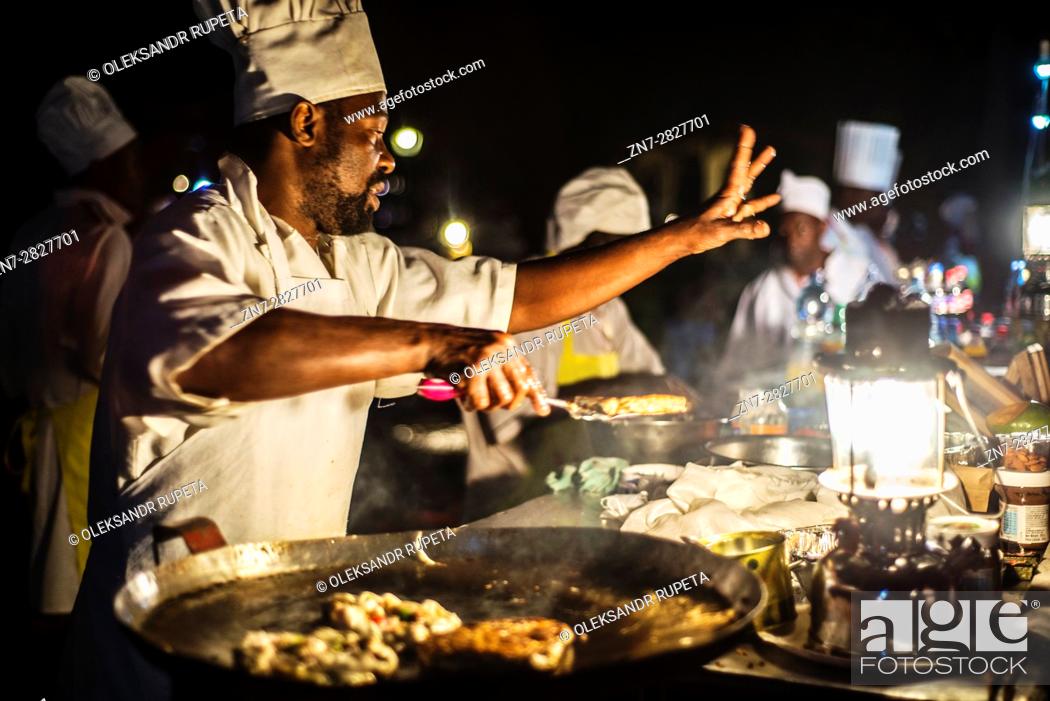 Stock Photo: Chefs prepare dishes during the Night food market at Forodhani Gardens in Stone Town, Zanzibar City, Zanzibar, Tanzania. This street food includes different.