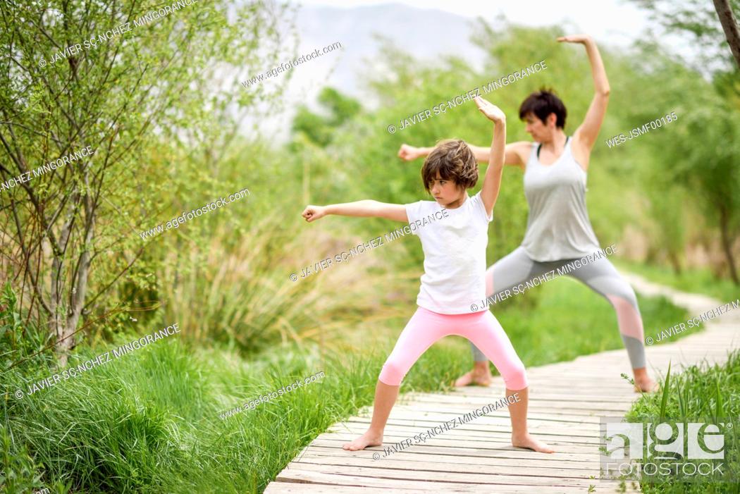 Stock Photo: Mother and daughter doing yoga on boardwalk.