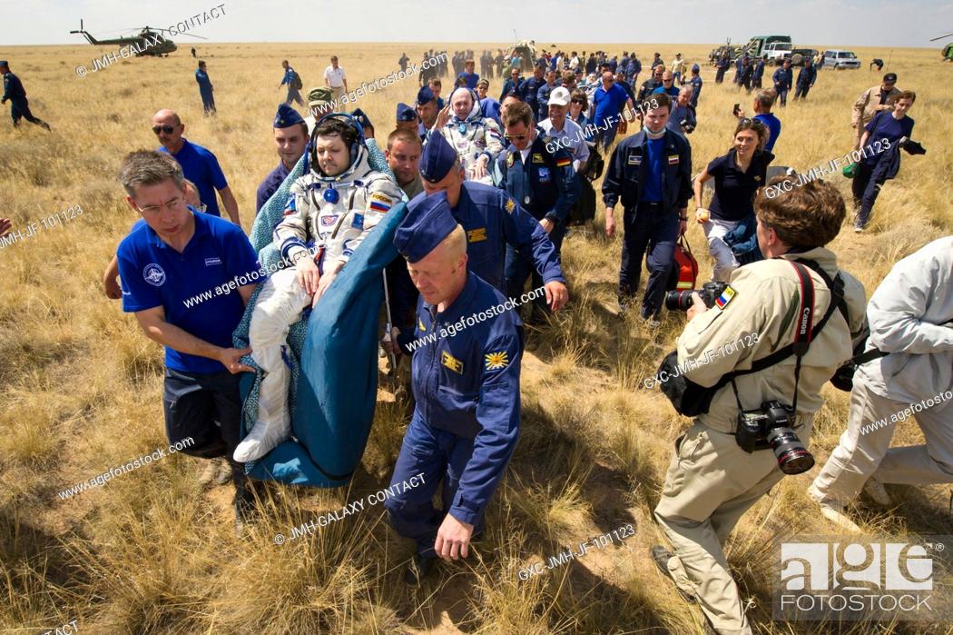 Stock Photo: Support and medical personnel carry Expedition 31 Commander Oleg Kononenko of Russia, foreground, and Flight Engineers Andre Kuipers of the European Space.