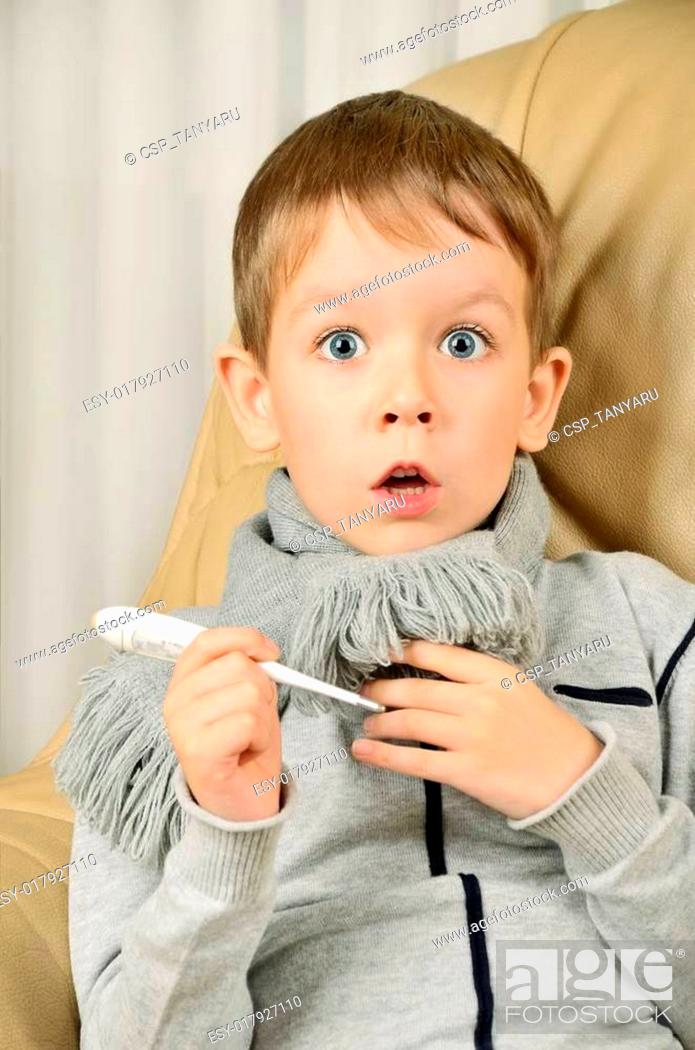 Stock Photo: frightened boy with a thermometer in his hands looking wide-eyed.