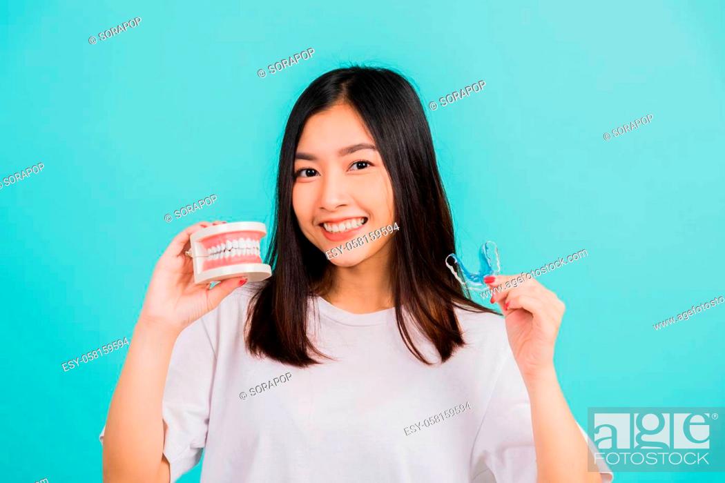 Stock Photo: Portrait young Asian beautiful woman smiling holding silicone orthodontic retainers for teeth retaining tools after removable braces.