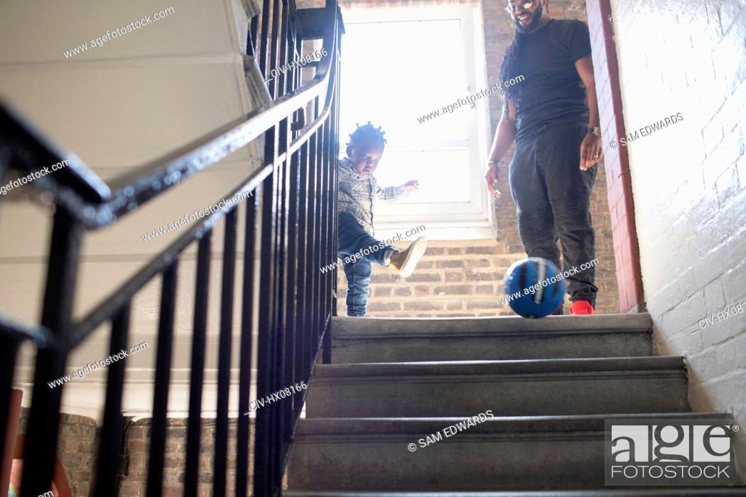 Stock Photo: Father and toddler son playing with soccer ball on stair landing.