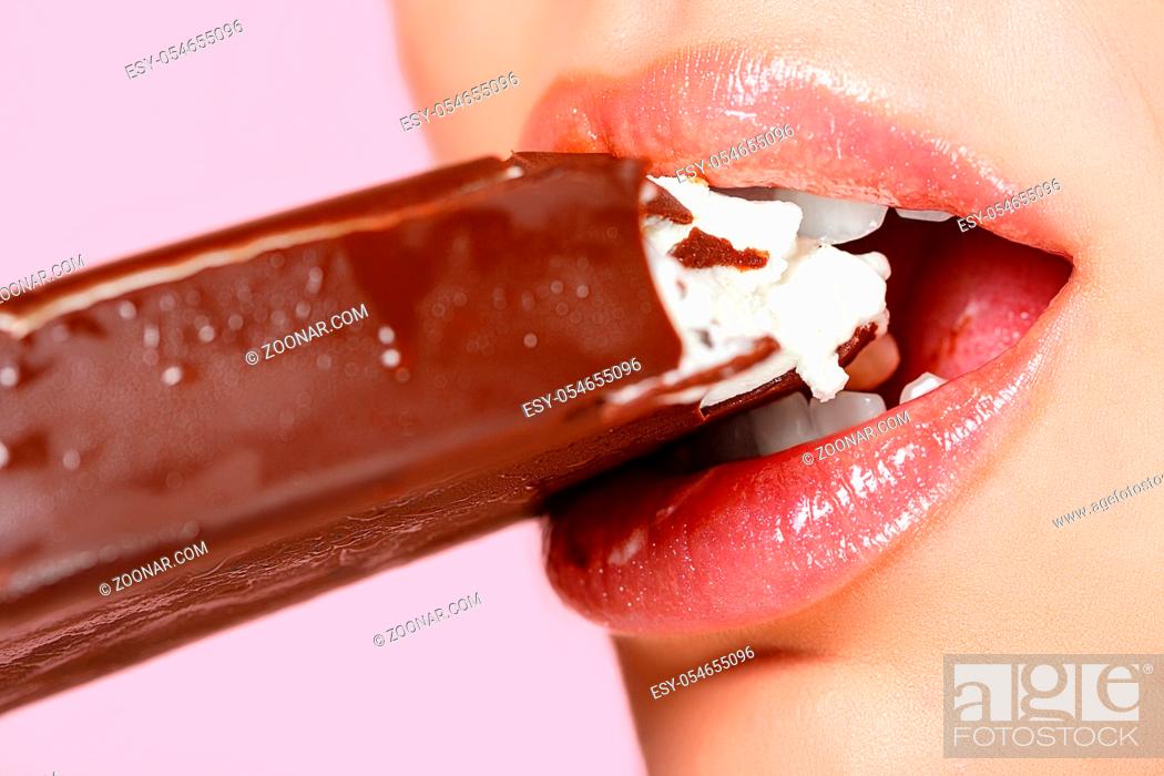 Stock Photo: face of a beautiful young girl close-up. she bites the ice cream with her mouth. on a pink isolated background.