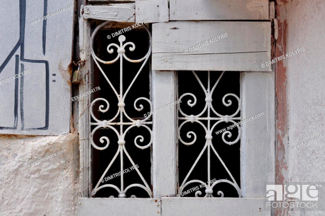 Stock Photo: Old window with decorative metal motif. Abandoned boarded up house.