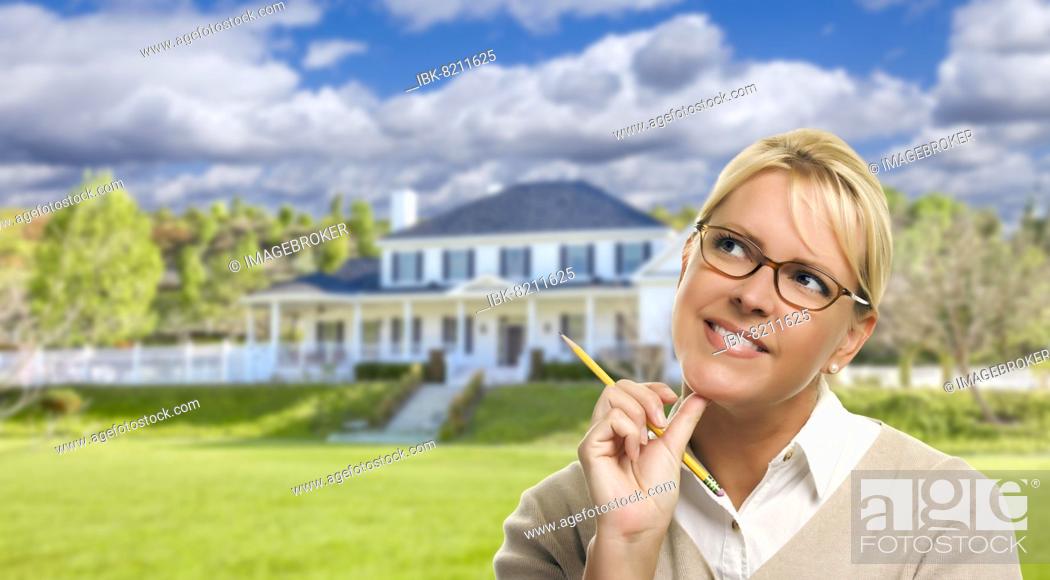 Stock Photo: Thinking young woman with pencil in front of beautiful house.