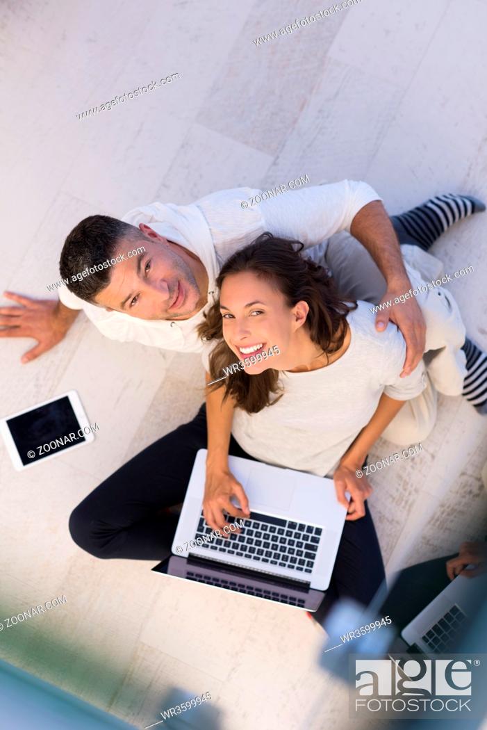 Stock Photo: top view of a young couple relaxing at home with tablet and laptop computers reading on the floor.
