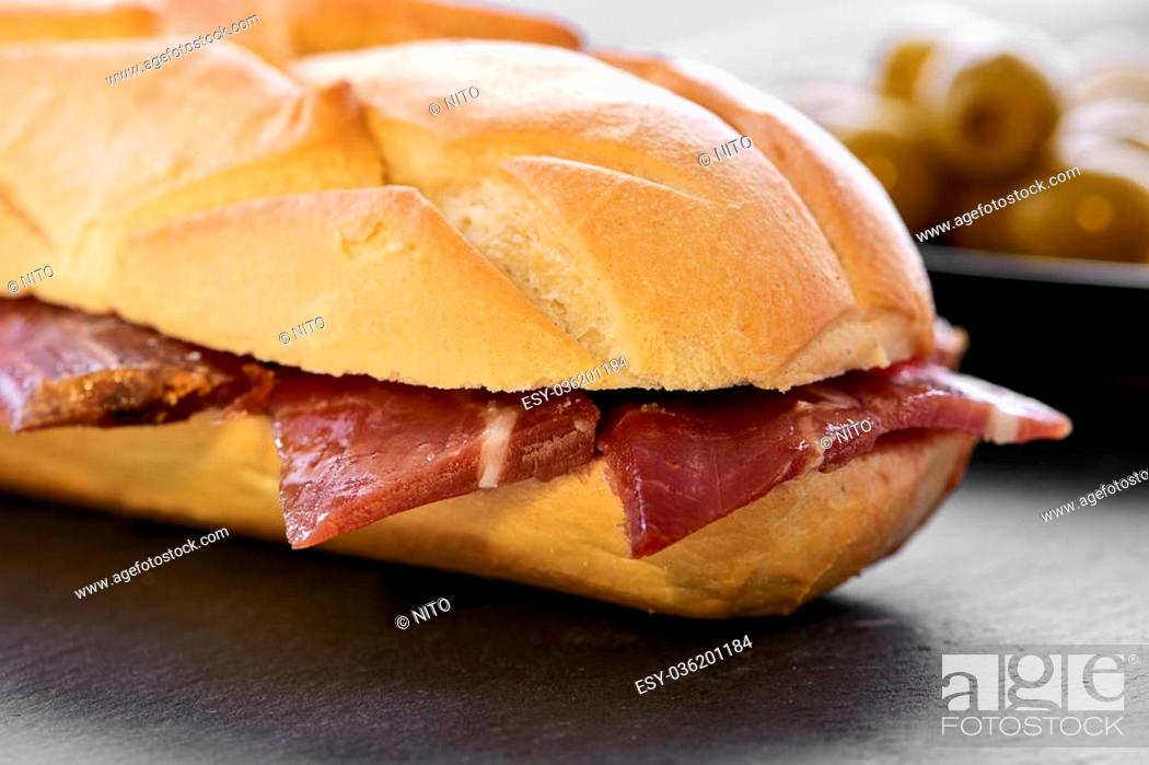 Stock Photo: closeup of a spanish bocadillo de jamon serrano, a serrano ham sandwich, on a slate stone background.