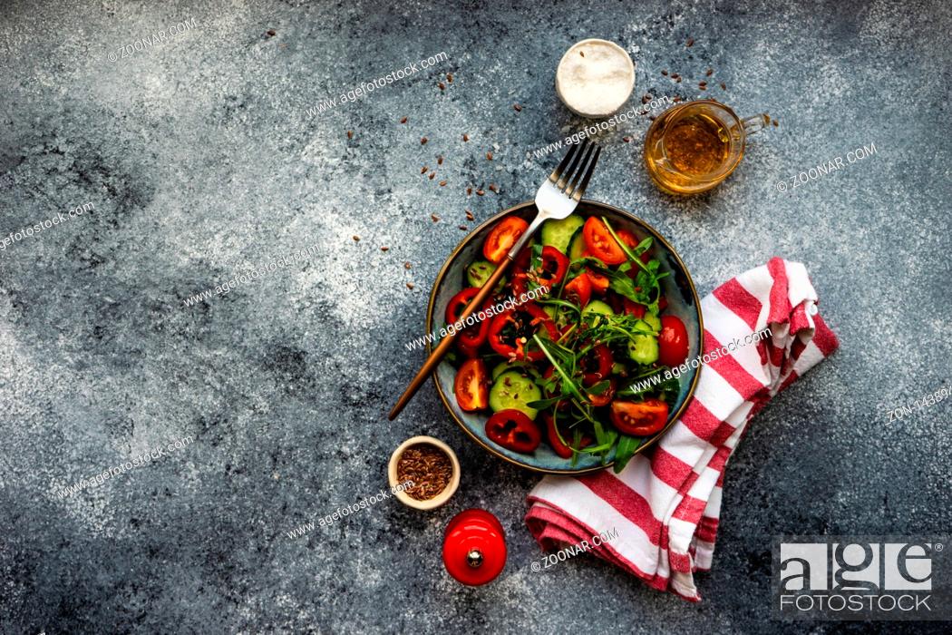 Stock Photo: Healthy vegetable salad with organic cucumber, tomatoes, bell pepper, rocket herb and flax seeds on stone background.