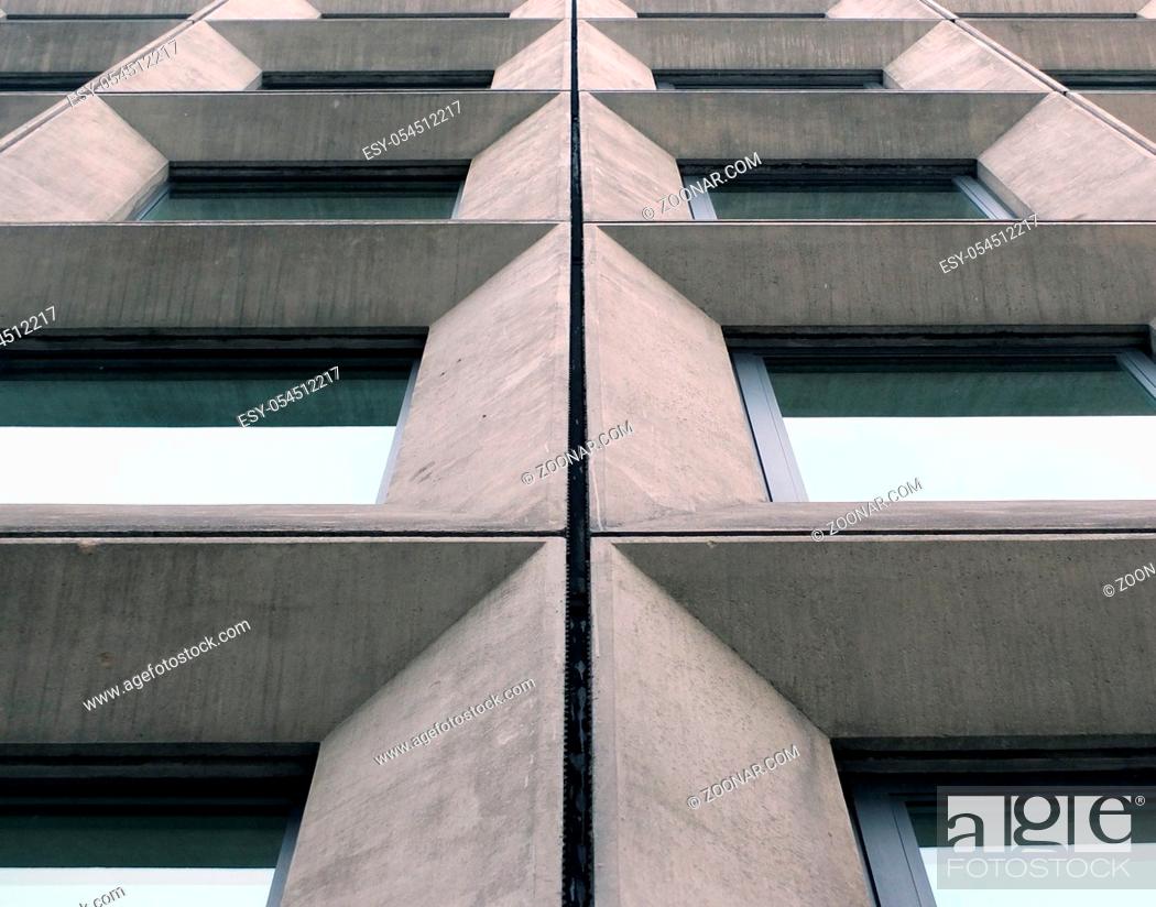 Stock Photo: perspective view of geometric angular concrete windows on the facade of a modernist 1960s brutalist style building.