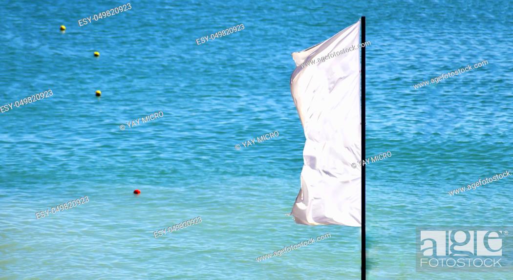Stock Photo: a waving white flag with a blue sea and signaling buoys in the background.