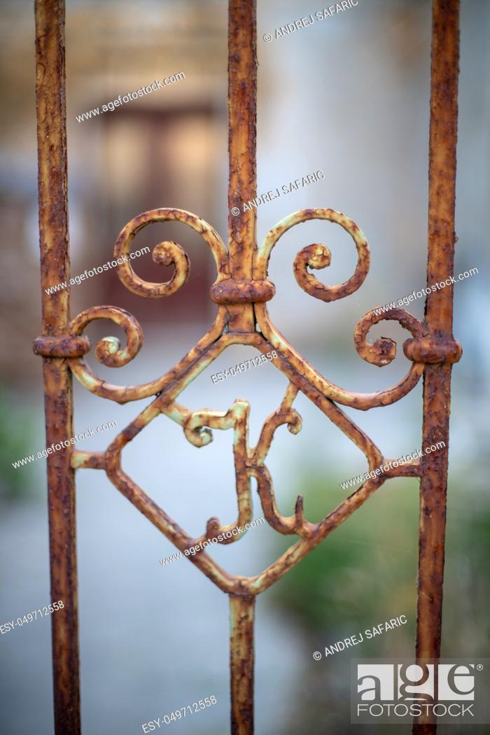 Stock Photo: Old rusty iron gate with letter K, abandoned house in background, rustic home decor, vintage blacksmith design.