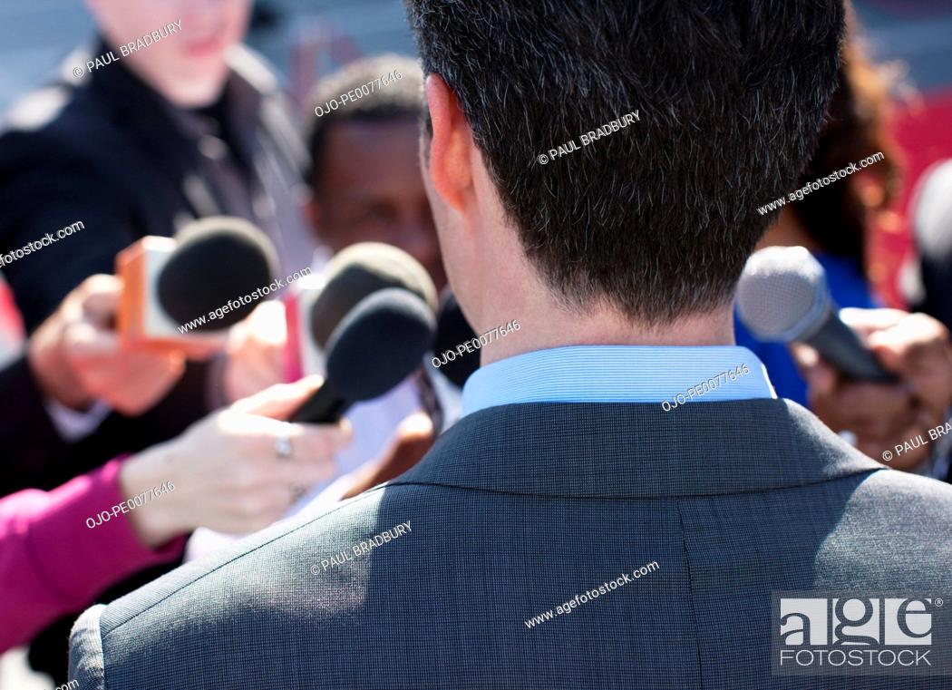Photo de stock: Politician talking into reporters' microphones.