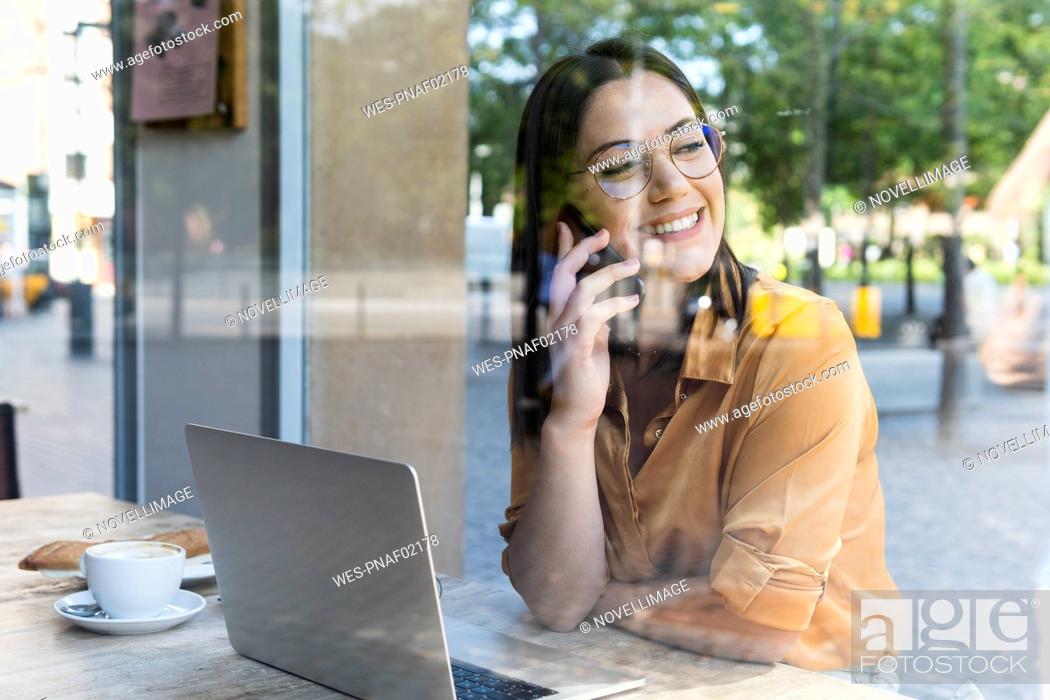 Imagen: Smiling female professional talking on smart phone in cafe.