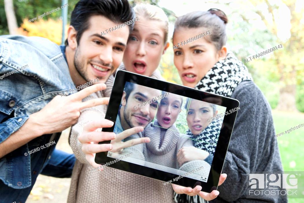 Stock Photo: Friends photographing themselves with digital tablet outdoors.