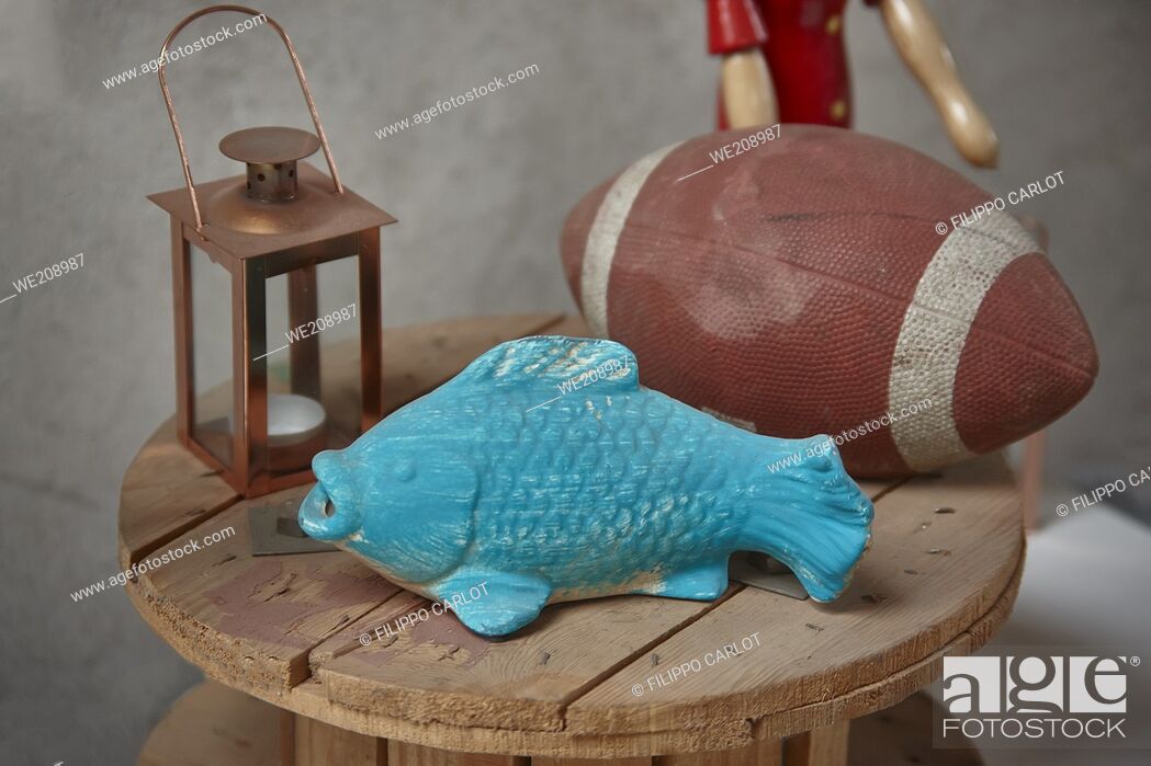 Stock Photo: Still life with some decorative objects on a wooden table among which: a blue fish and a rugby ball.