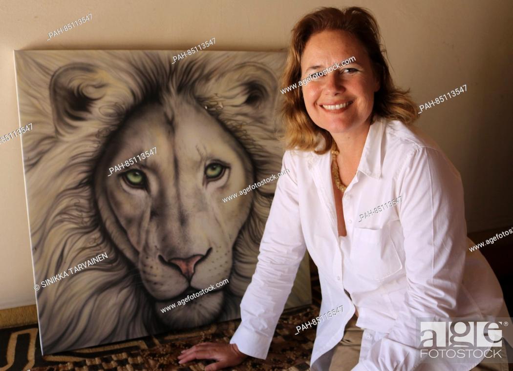 Stock Photo: CEO of the Global White Lion Trust, Linda Tucker, who operates a conservancy for while lions in South Africa, sits in front of a painting of a white lion in.