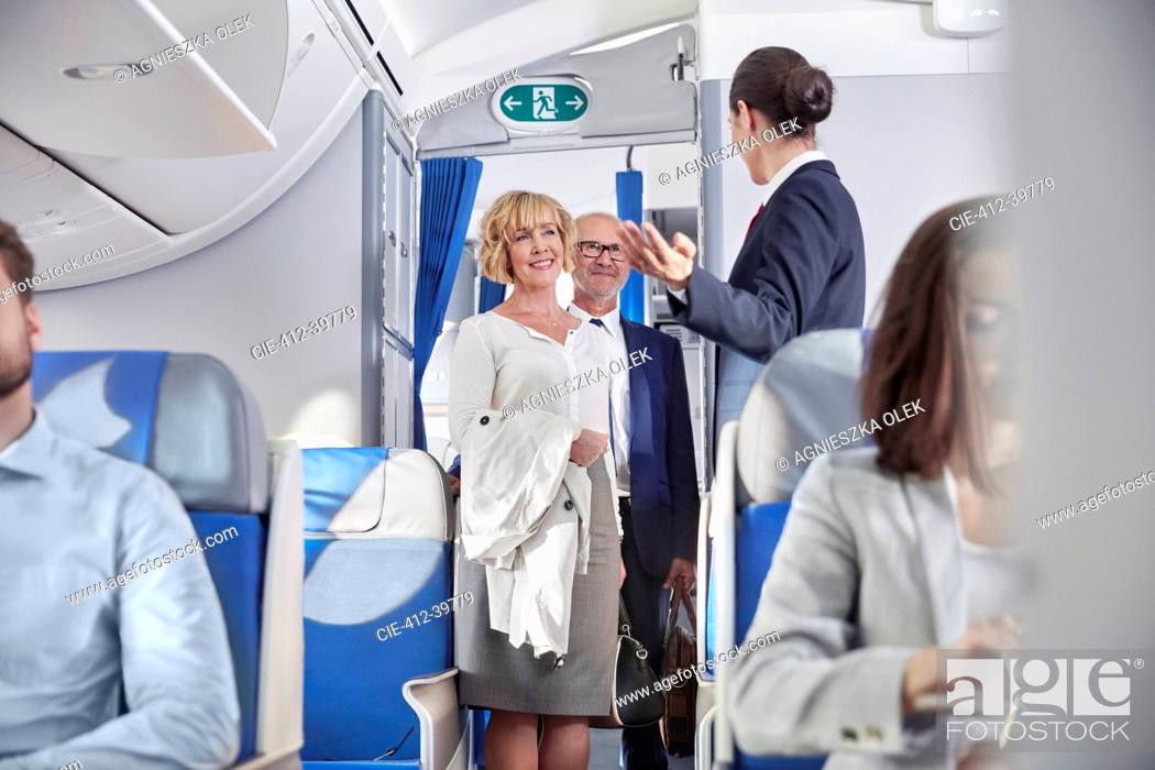 Stock Photo: Flight attendant greeting passengers boarding airplane.