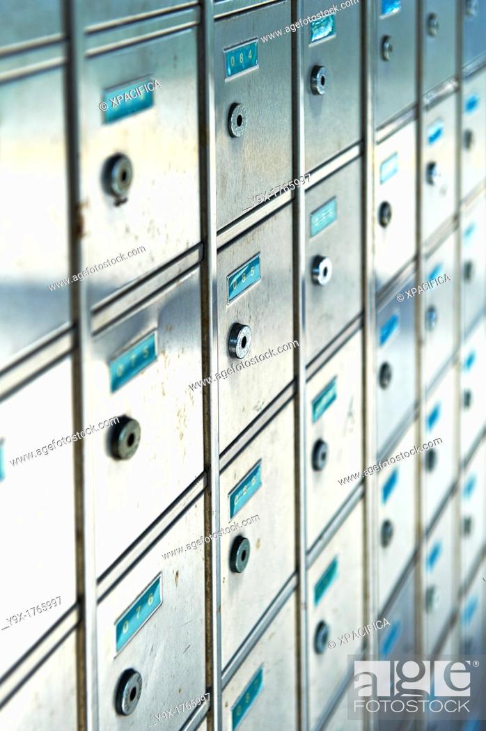 Imagen: A row of small metal mailboxes with teal number tags.