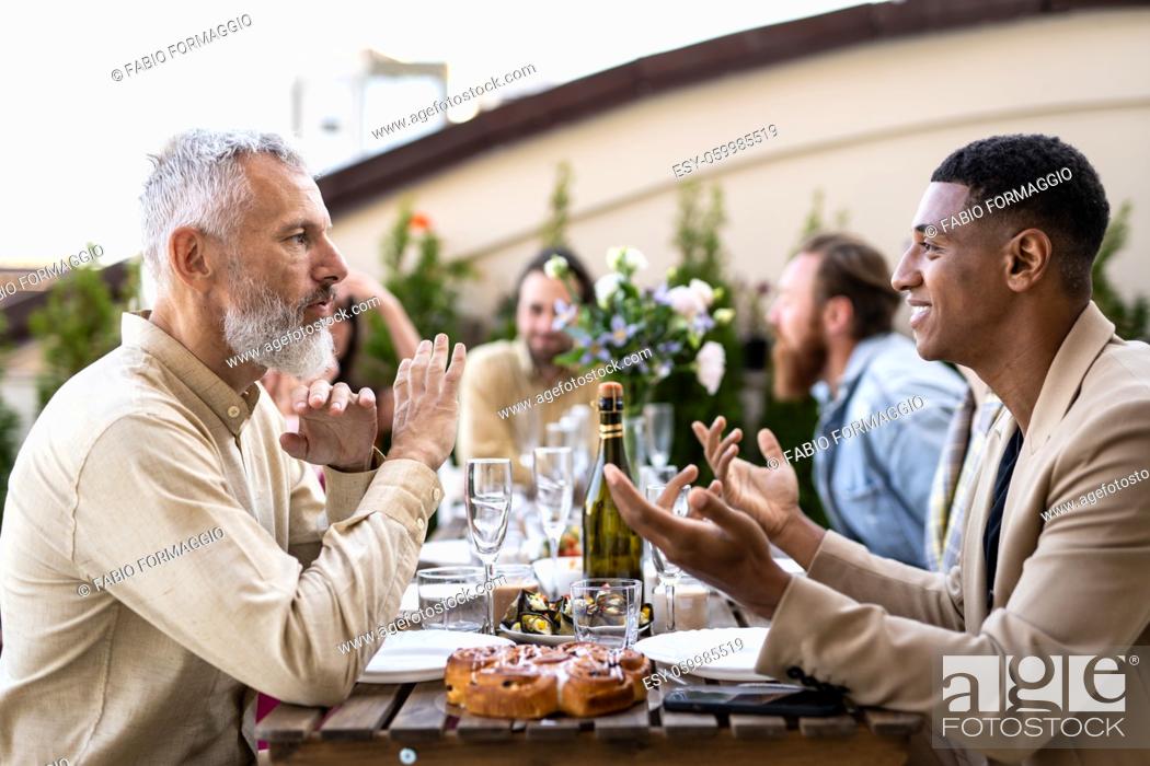 Stock Photo: Storytelling footage of a multiethnic group of people dining on a rooftop. Family and friends make a reunion at home.