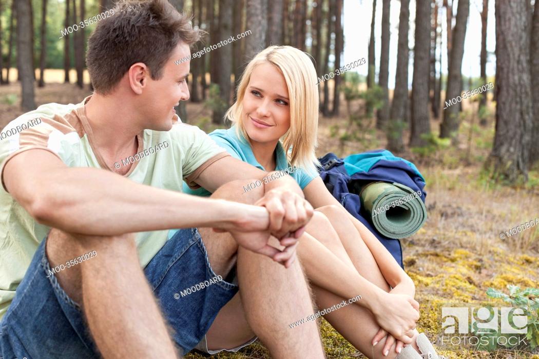 Stock Photo: Hiking couple looking at each other while relaxing in forest.