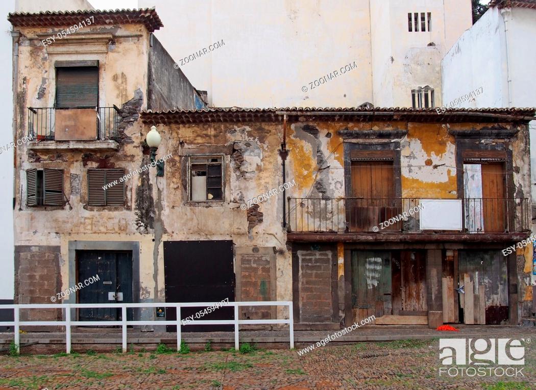 Photo de stock: a row of derelict abandoned houses and commercial properties on a street with boarded up doors and windows and crumbling walls.