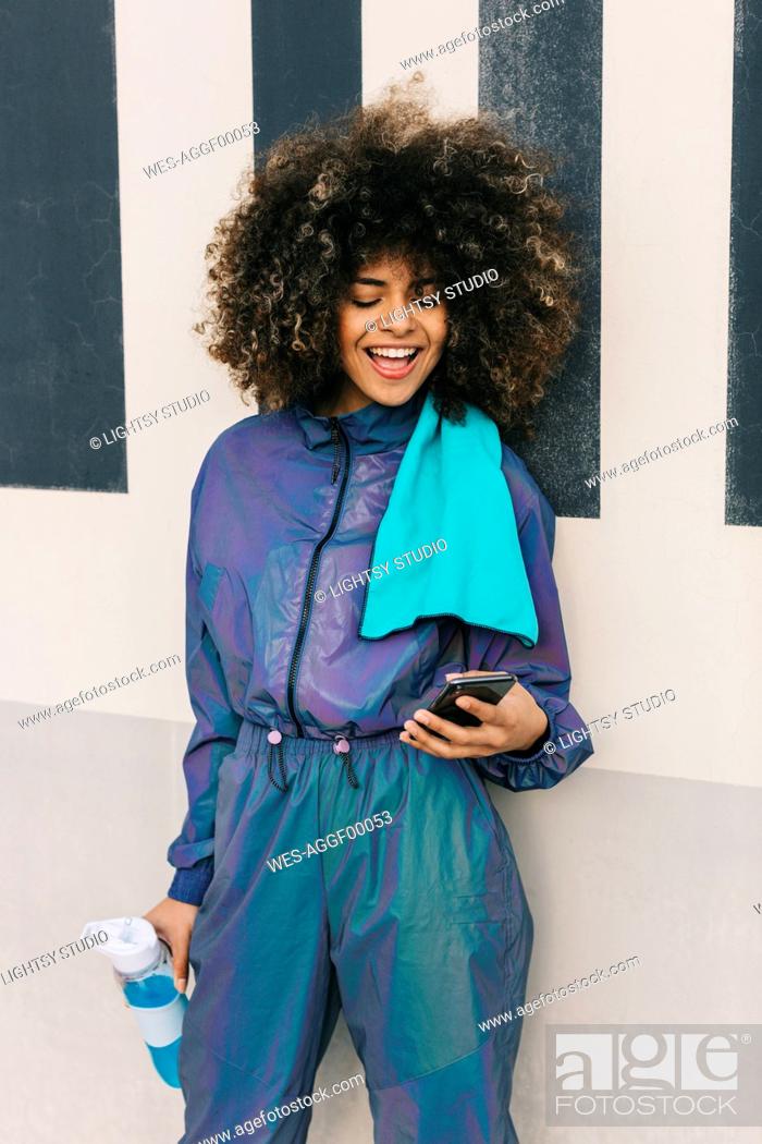 Stock Photo: Happy young woman wearing tracksuit and using cell phone outdoors.