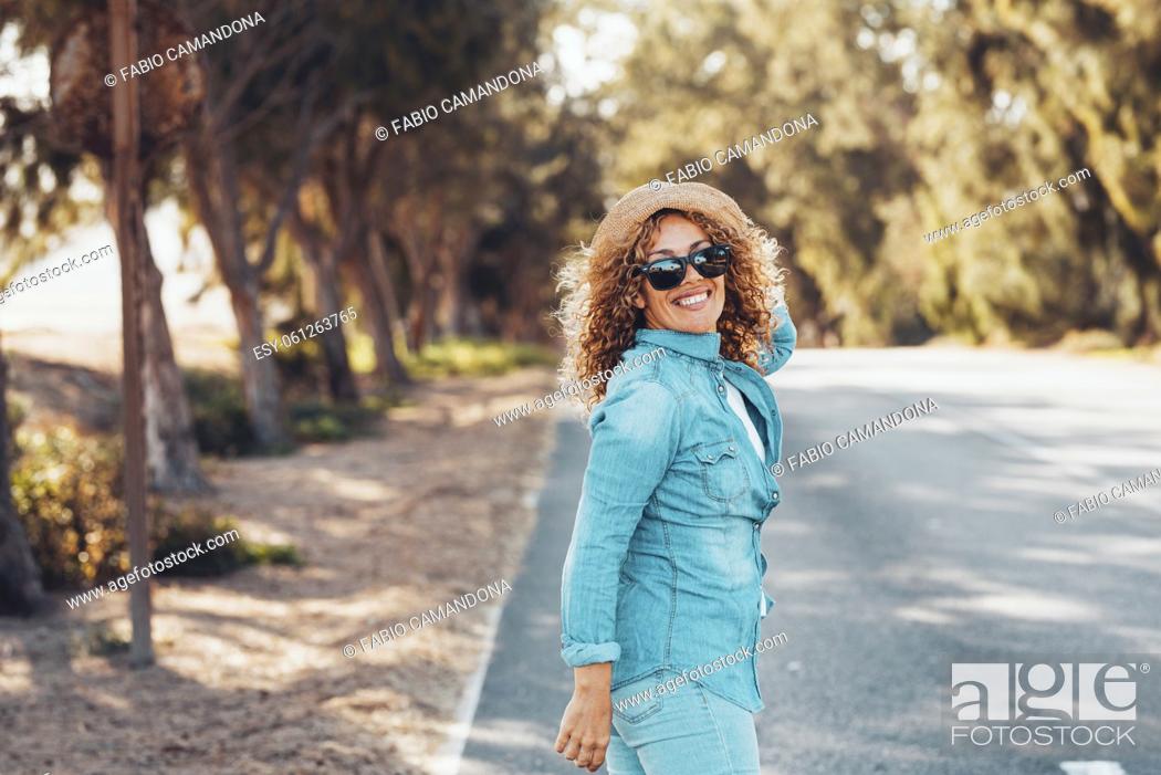 Photo de stock: Tourist walk on the road and turn back to smile at her friends enjoying outdoor leisure activity with long street in background.