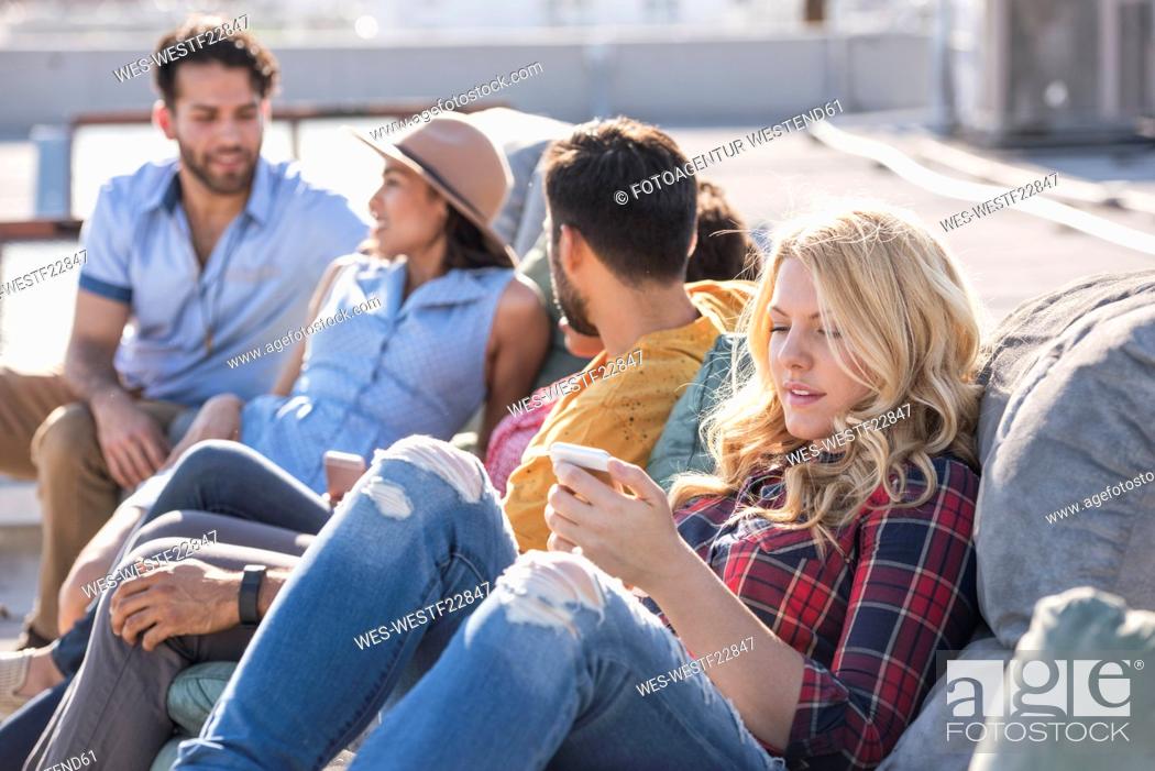 Stock Photo: Friends having a rooftop party and using smart phione.