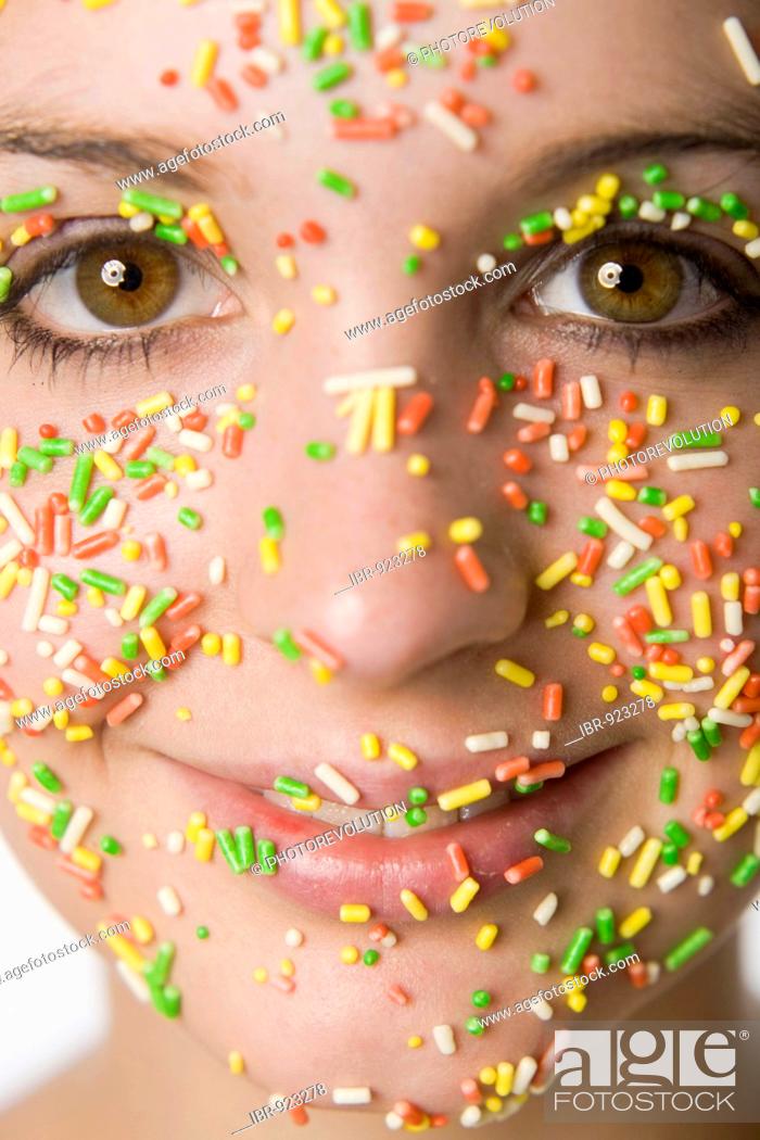 Stock Photo: Coloured crumbles are sticking to a young woman's face.