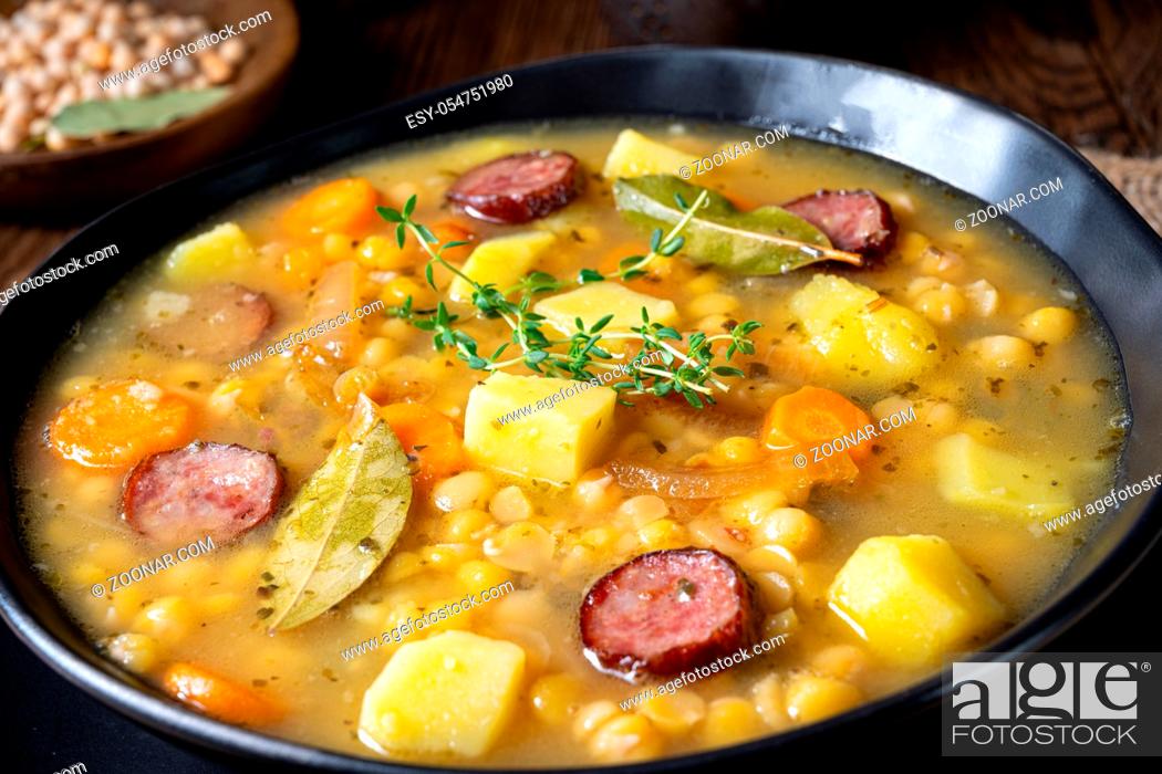 Stock Photo: Rustic pea soup with bacon and sausages.