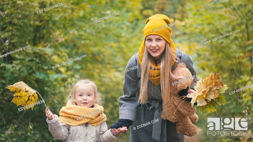 Stock Photo: Mom spends time with her daughter - walks in autumn park and collect leaves, close up, telephoto.