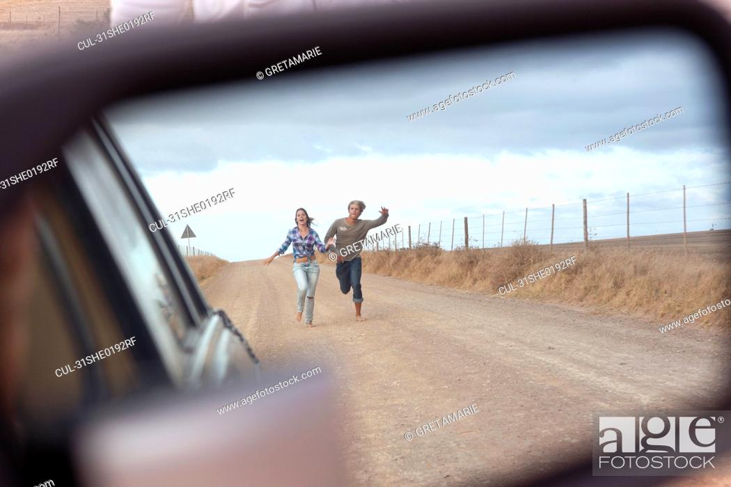Stock Photo: Couple running behind car.