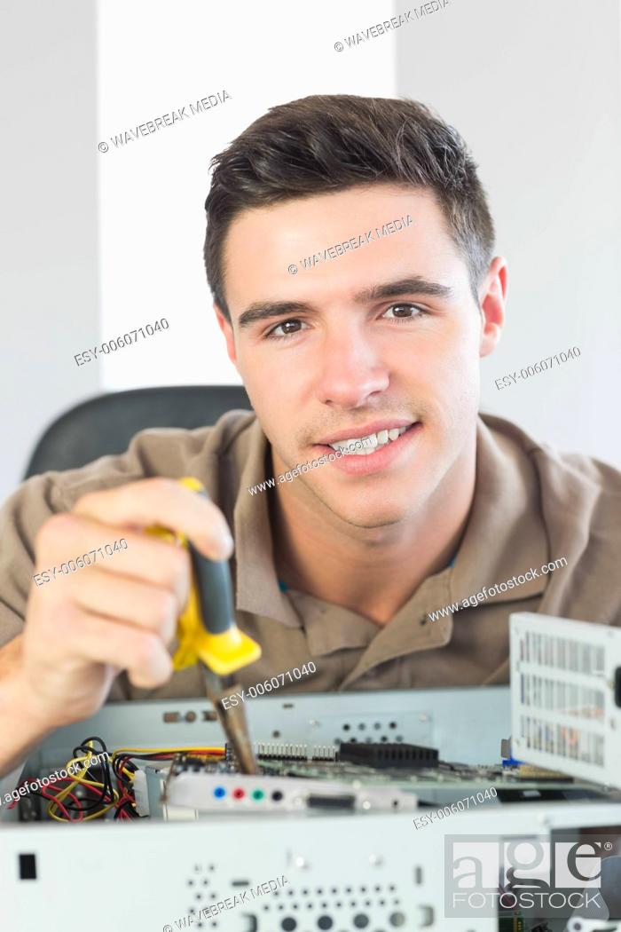 Stock Photo: Handsome happy computer engineer repairing open computer.